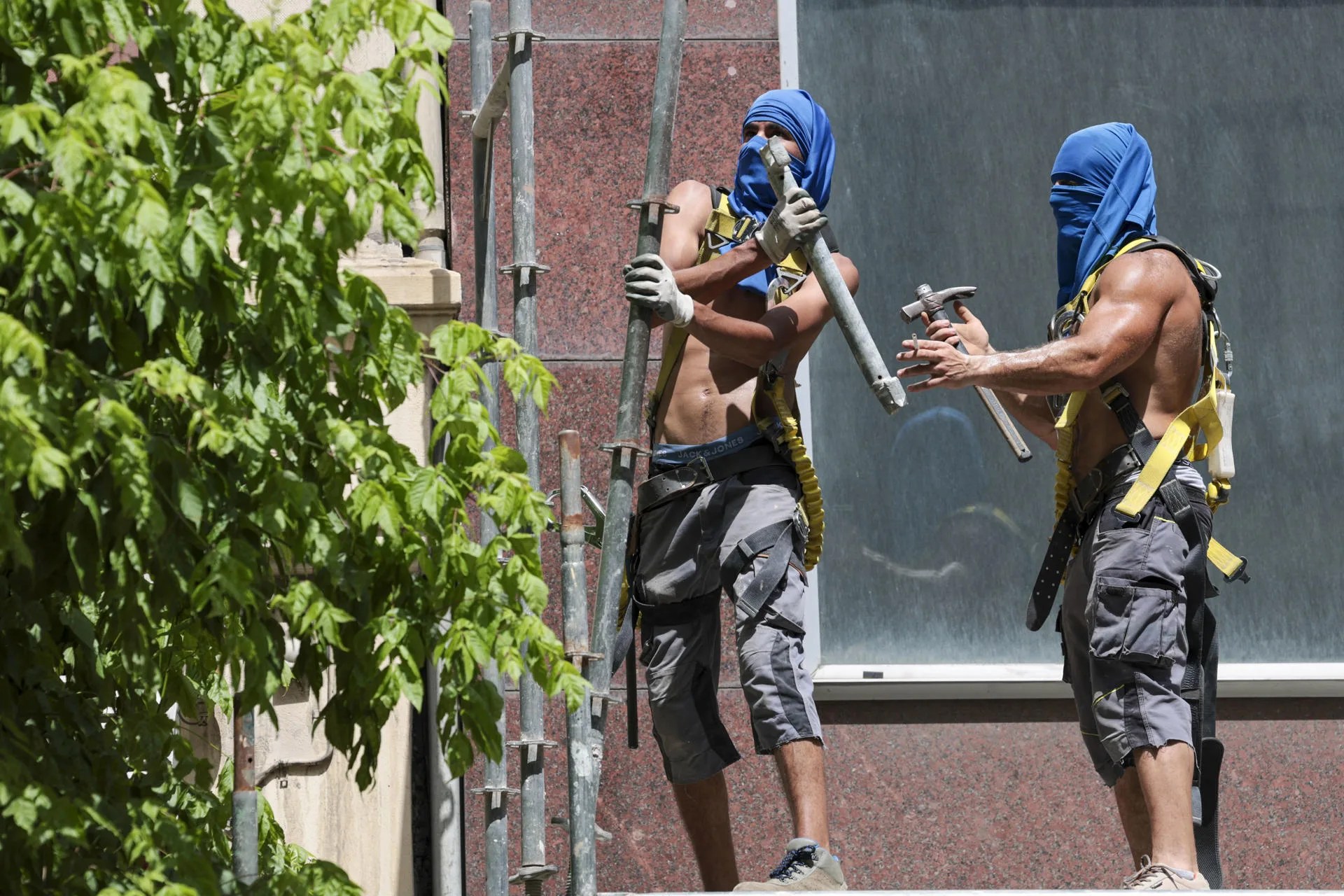 Trabajadores en un andamio se protegen la cabeza para aliviar as temperaturas extremas. EFE/Luis Tejido/Archivo