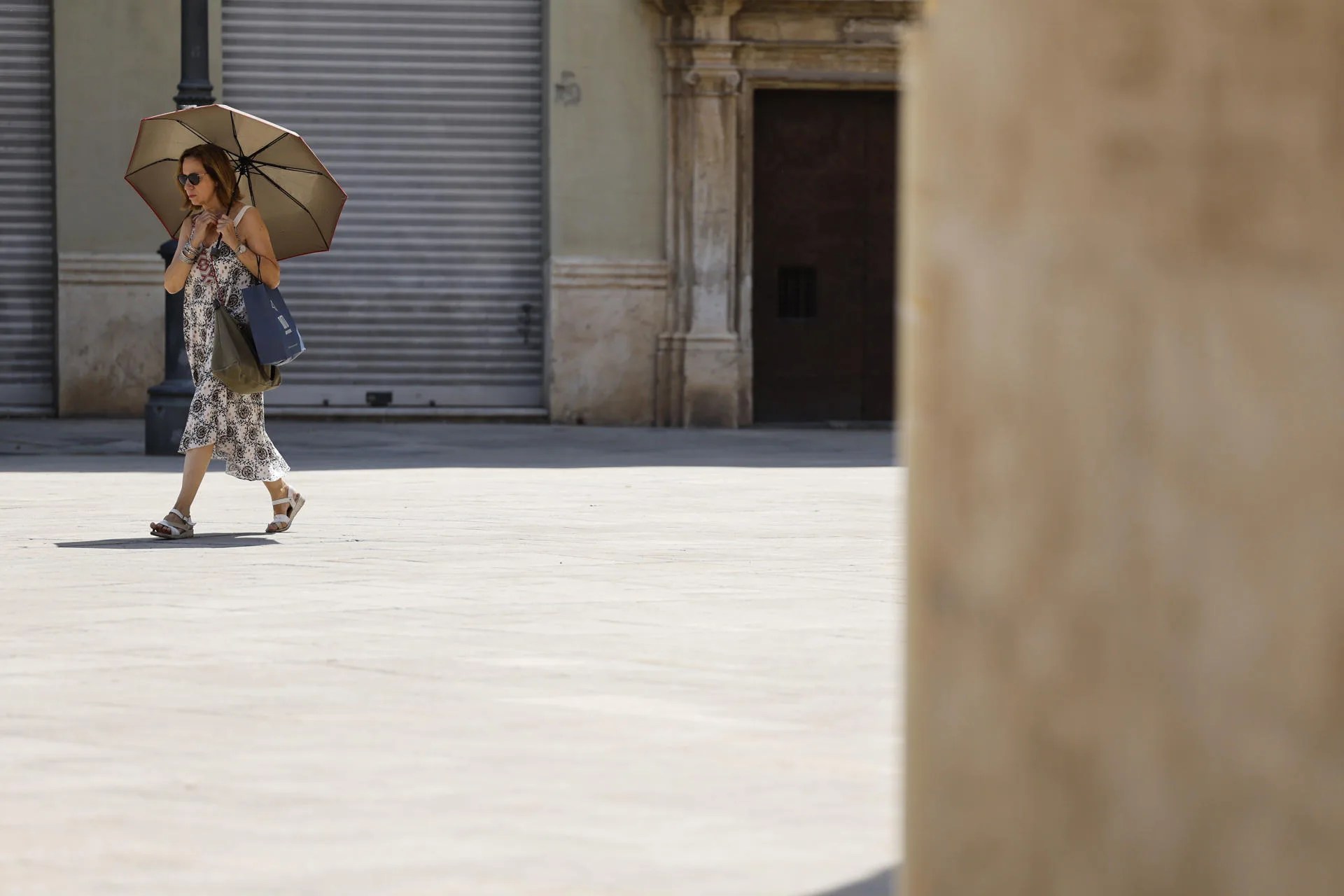 Una mujer ser protege del sol con un paraguas en las calles de Valencia. . EFE/ Ana Escobar