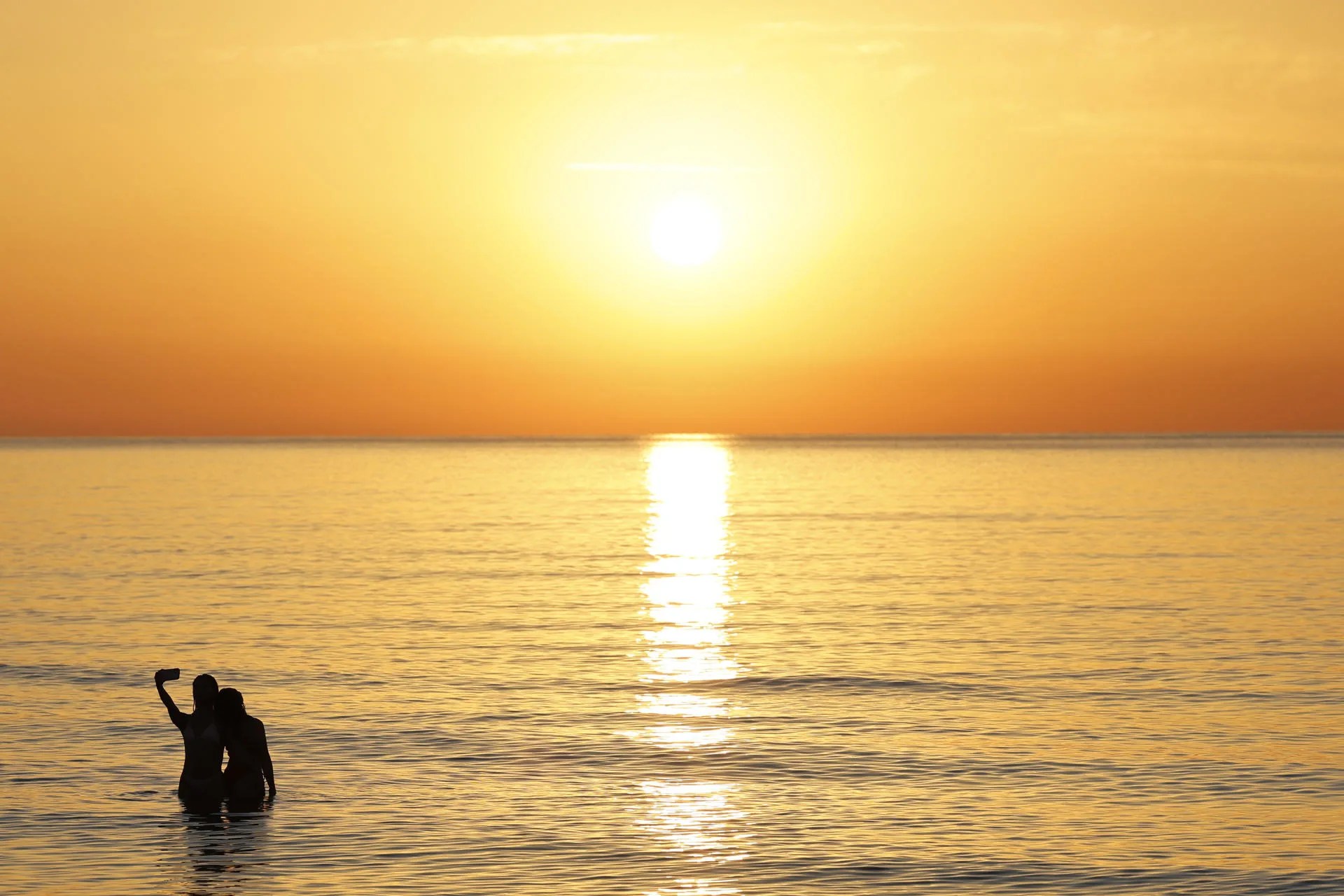 Dos jóvenes se hacen un selfie al amanecer en la playa de la Malvarrosa. EFE/Ana Escobar/Archivo