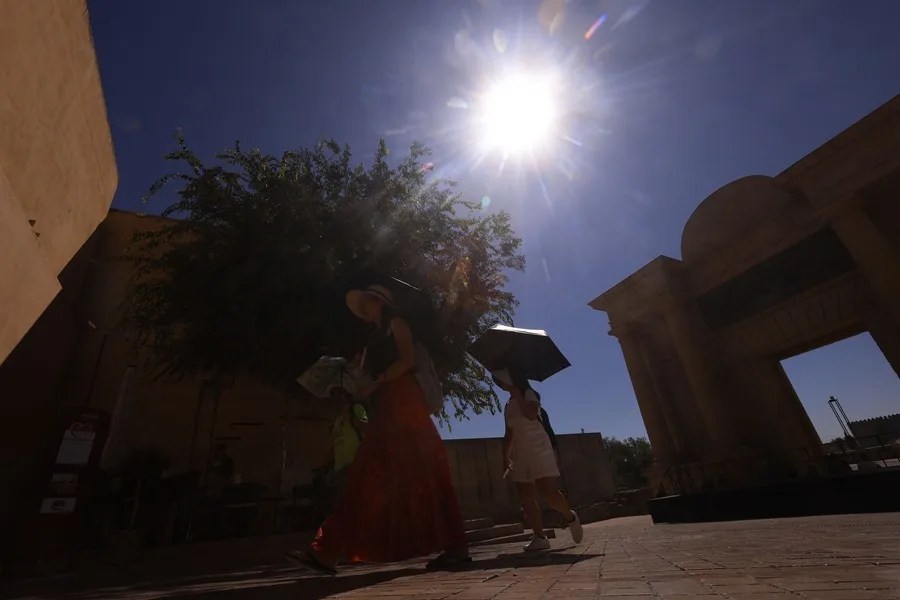 Turistas se protegen con paraguas para aliviar las altas temperaturas