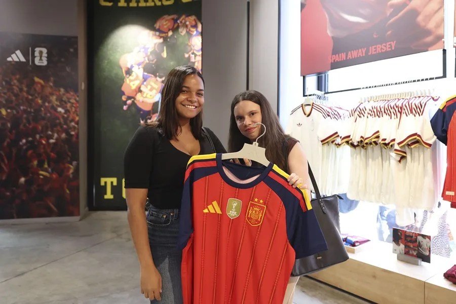 Dos chicas muestra la camiseta que este martes a puesto a la venta Adidas, con las dos estrellas y el escudo actualizado tras haber ganado el Mundial 2026.