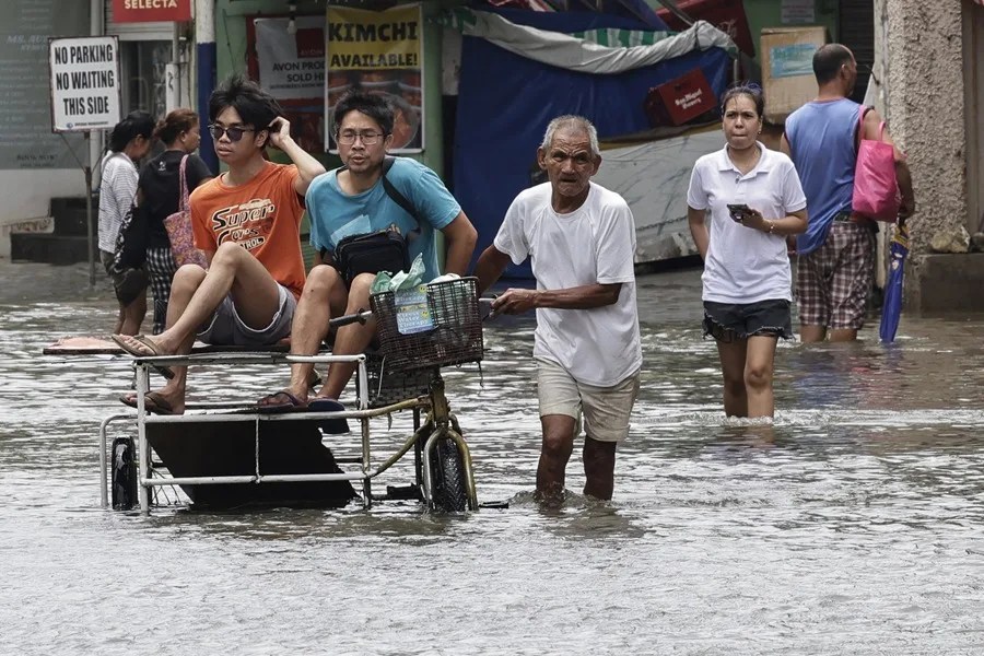Un grupo de personas en bicicleta atraviesa una zona inundada en Manila.