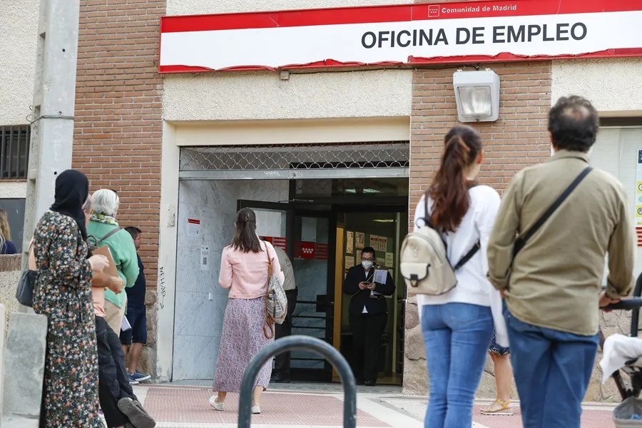 Varias personas hacen cola para acceder a una oficina de empleo en Madrid.