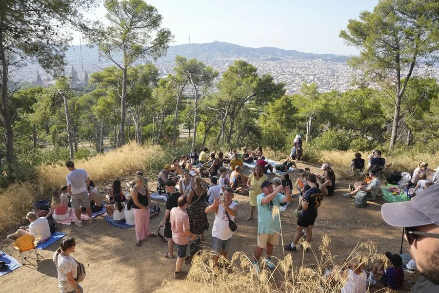 Varias personas esperan el eclipse solar en el Castillo de Monjuic de Barcelona, este miércoles.