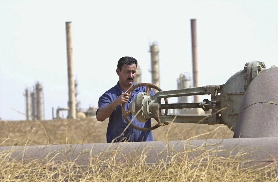 Un trabajador petrolero abriendo una válvula en una refinería iraquí