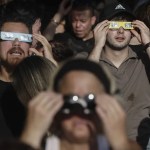 Una multitud de personas con gafas protectoras espera del comienzo del eclipse de Sol en Madrid este miércoles.
