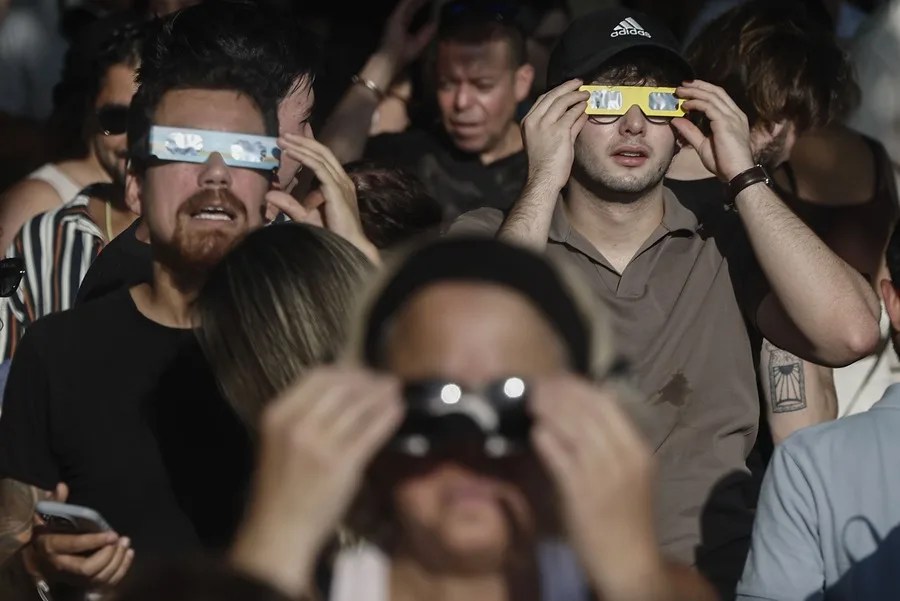 Una multitud de personas con gafas protectoras espera del comienzo del eclipse de Sol en Madrid este miércoles.