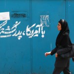 Una mujer pasa junto a un grafiti en persa que dice: «Tenemos una enemistad ancestral con Estados Unidos», en una calle del centro de Teherán, Irán.