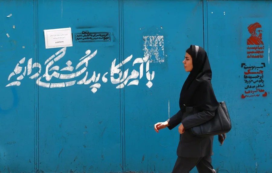 Una mujer pasa junto a un grafiti en persa que dice: «Tenemos una enemistad ancestral con Estados Unidos», en una calle del centro de Teherán, Irán.
