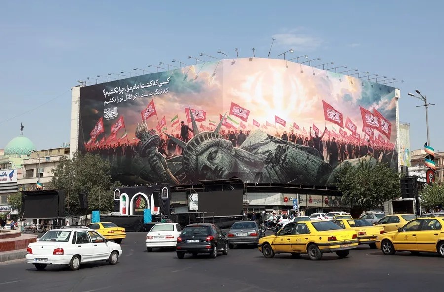 Vehículos pasan junto a una valla publicitaria antiestadounidense en la plaza Enghelab, en el centro de Teherán.