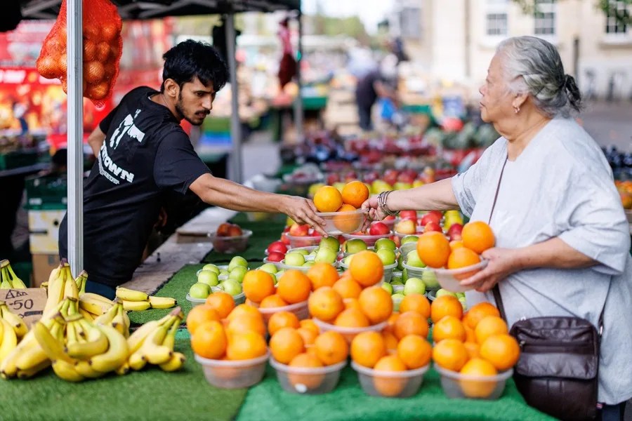 Una mujer compra fruta en un mercado en Londres.