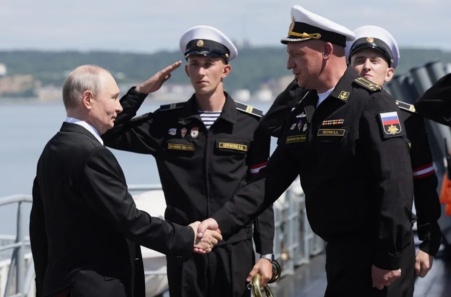 El presidente ruso, Vladímir Putin (i.), saluda al comandante del crucero de misiles de la Guardia "Varyag", Konstantín Petrov, a su llegada a bordo del buque, en la región de Sajalín, Rusia.