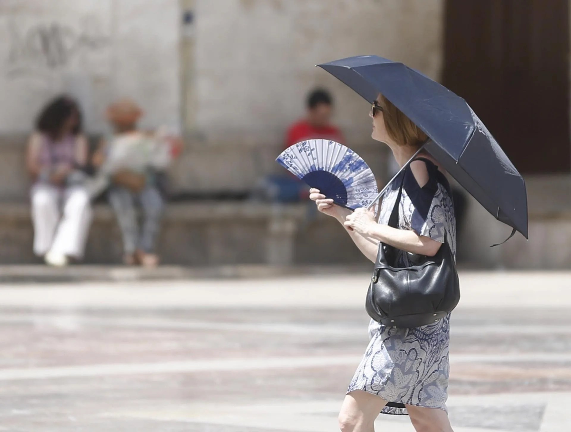 Una mujer se abanica y se protege del sol con un paraguas en Valencia.EFE/ Kai Forsterling/Archivo