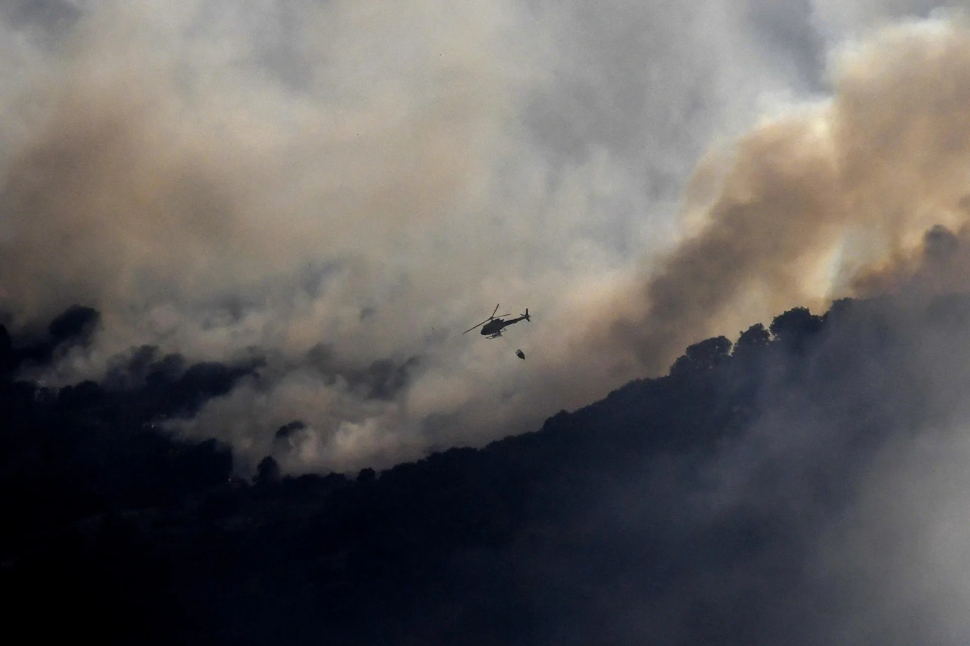 Una treintena de medios de extinción mantiene este domingo las labores para tratar de consolidar el perímetro de un incendio forestal declarado el sábado en el término municipal de Navas de San Antonio, en Segovia, por un vehículo que comenzó a arder en el arcén de la autopista AP-6. EFE/Pablo Martín