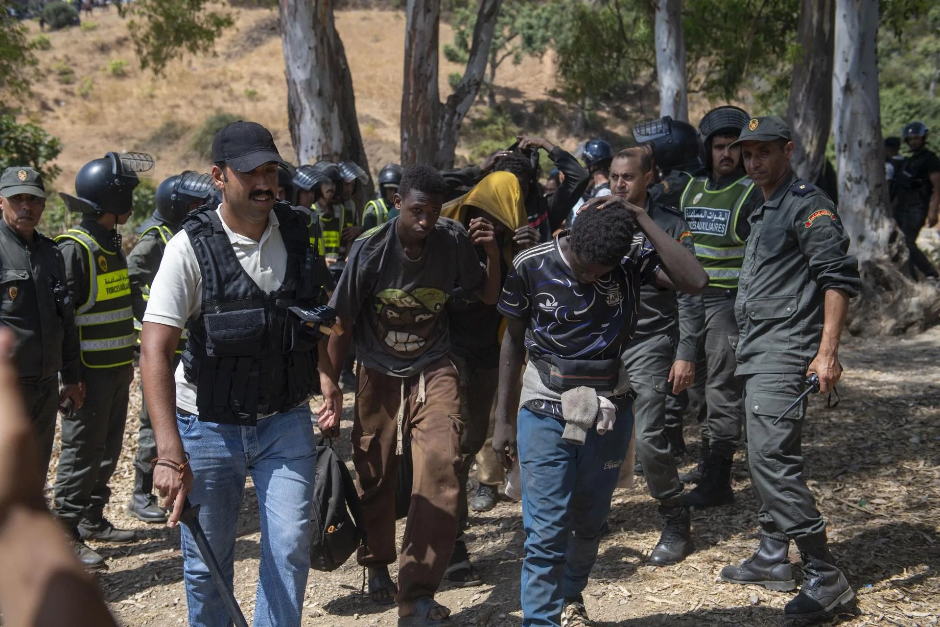 Moroccan security forces arrest migrants as they prevent attempts by hundreds of sub-Saharan African and Sudanese migrants gathered near Fnideq (Castillejos), Morocco, to enter the Spanish city of Ceuta, 15 August 2026. EFE-EPA/JALAL MORCHIDI