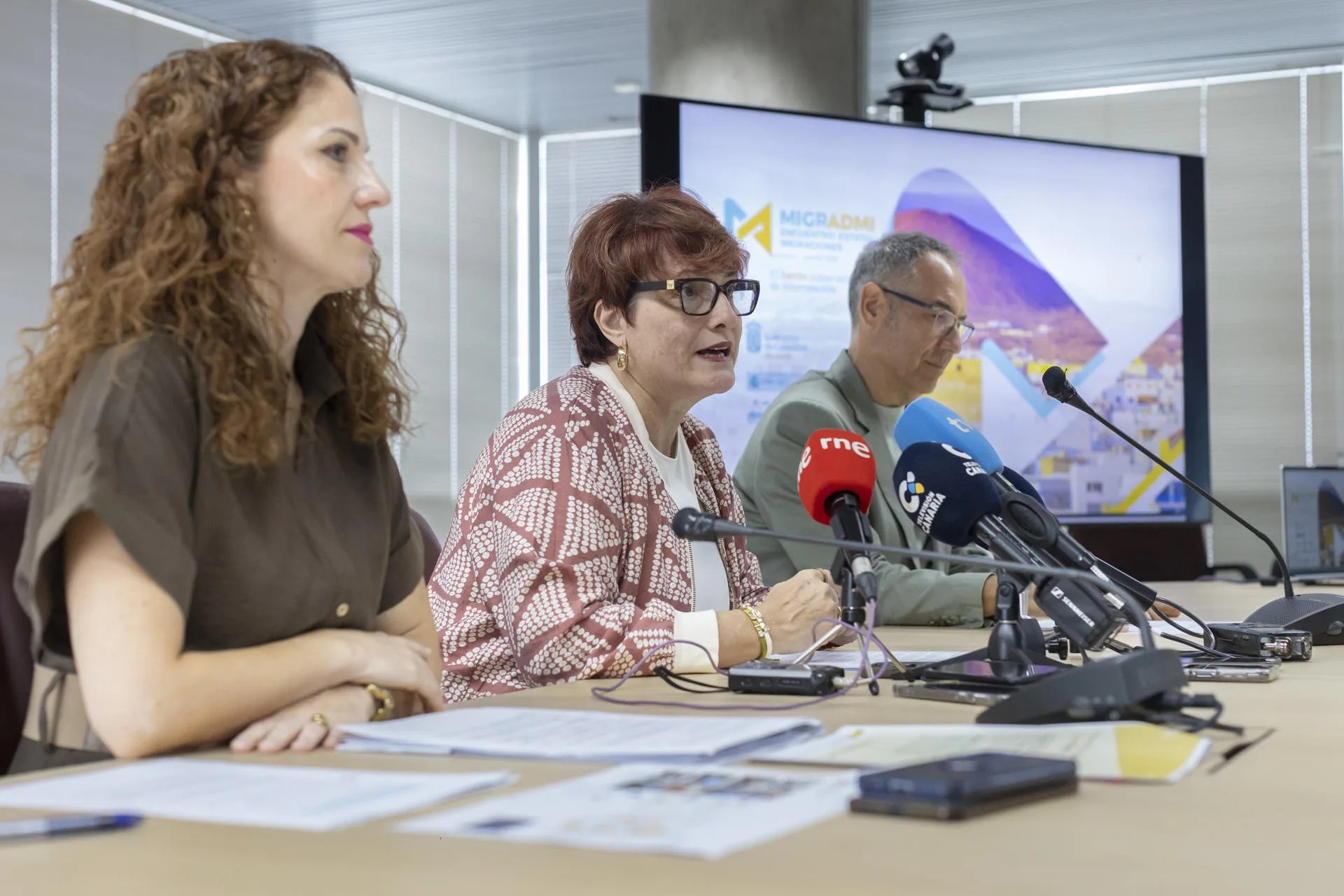 La consejera de Bienestar Social, Igualdad, Juventud, Infancia y Familias, Candelaria Delgado (c), acompañada por la directora general de Servicios Sociales e Inmigración, Elisabet Santana (i), y el director académico del Programa Canarias Convive, Vicente Manuel Zapata (d), presentaron este jueves el programa del Encuentro Estatal de Migraciones (Migradmi) que tendrá lugar en septiembre. EFE/ Quique Curbelo