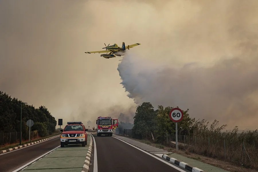 Un hidroavión realiza una descarga de agua sobre la carretera CV-500 ante el avance del incendio forestal declarado este jueves en la Gola de Pujol.