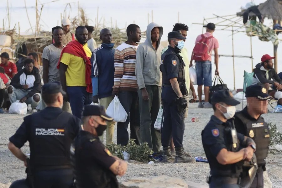 Agentes de policía escoltan a migrantes desde la playa del Trampolín hasta un centro de acogida en Ceuta, España.