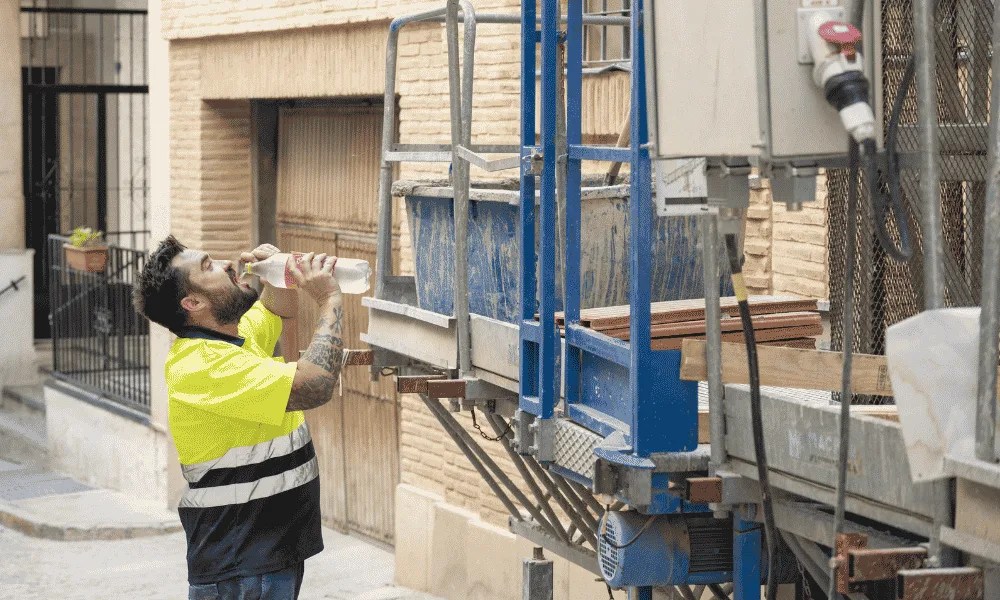 Un trabajador se refresca, bebiendo agua de una botella.