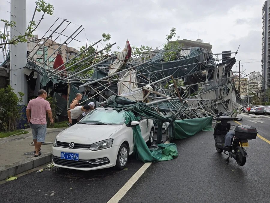 Un grupo de personas observa un coche dañado al paso del tifón Dolphin por Zhejiang, China.