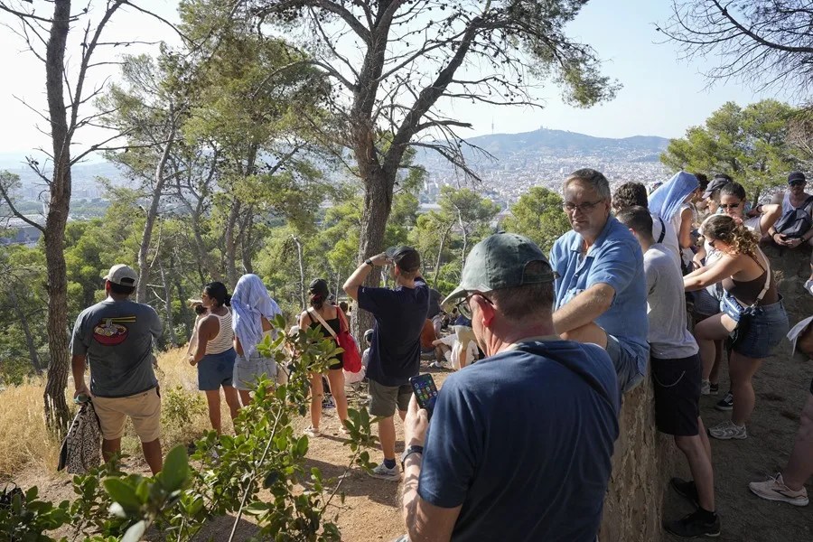 Varias personas esperan el eclipse solar en el Castillo de Monjuic de Barcelona, este miércoles.