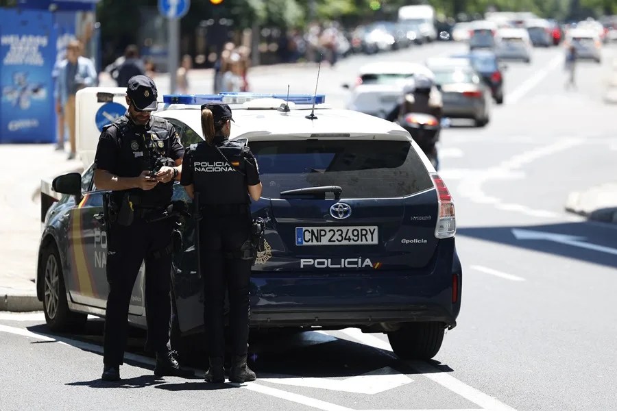 Una pareja de la Policía Nacional junto al coche patrulla.
