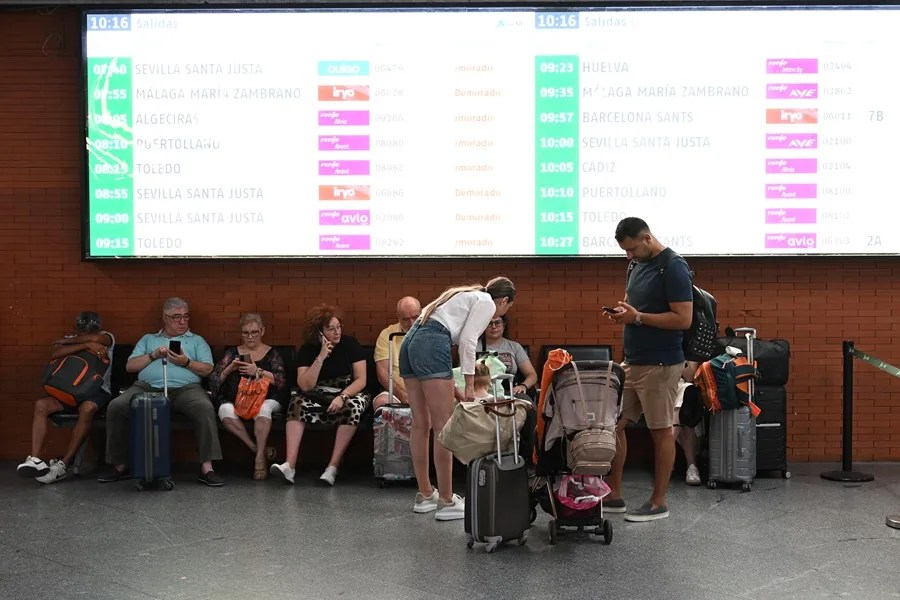 Varios pasajeros aguardan la salida de su tren en la Estación de Atocha, en Madrid.