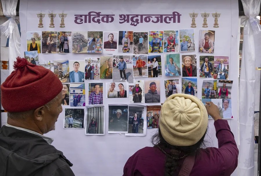 Varias personas observan fotografías de las personas que perdieron la vida en las riadas cerca de la frontera entre Nepal y el Tíbet.