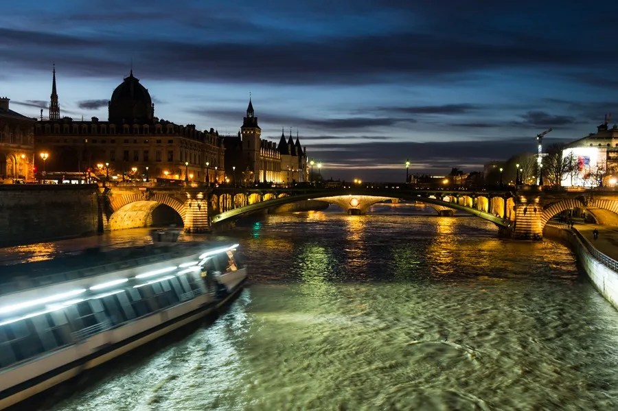 Vista nocturna de un barco turístico en el río Sena, frente a la Île de la Cité (izquierda), en el centro histórico de París