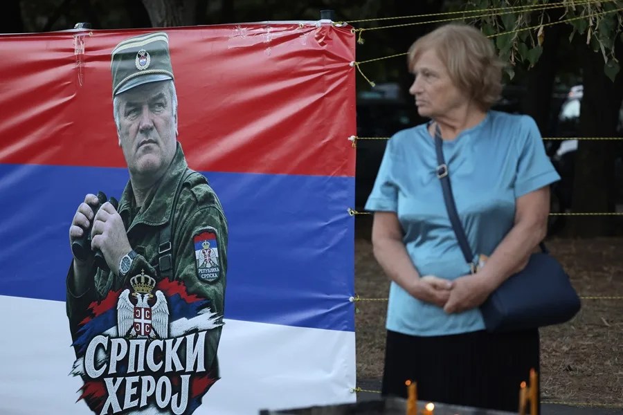 Una mujer permanece junto a una pancarta con la inscripción «Héroe serbio» y la imagen de Ratko Mladić durante su funeral en Belgrado