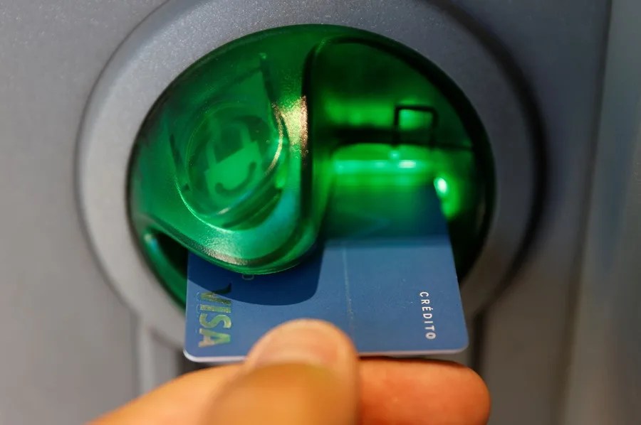Una persona saca dinero de un cajero de una entidad bancaria,