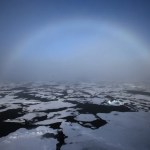 Un arco iris apareciendo en el horizonte en el Ártico