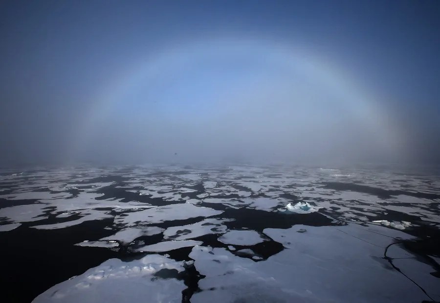 Un arco iris apareciendo en el horizonte en el Ártico