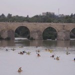 Turistas observan desde el Puente Romano de Córdoba las piraguas que pasan este sábado por el río Guadalquivir,