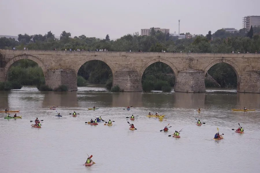 Turistas observan desde el Puente Romano de Córdoba las piraguas que pasan este sábado por el río Guadalquivir,