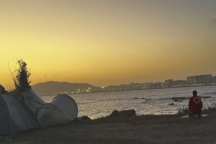 Un migrante reza al amanecer en la playa del Trampolín en Ceuta.