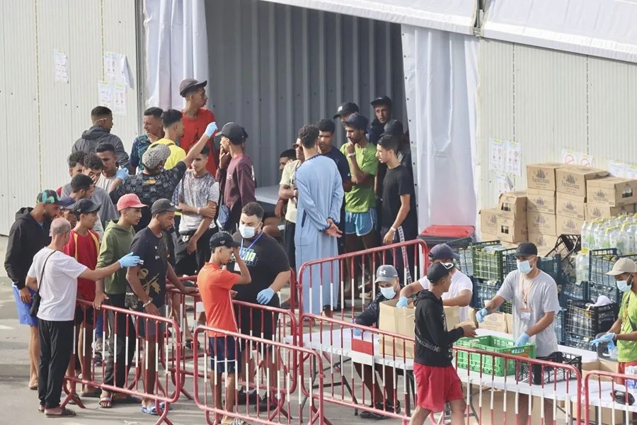 Se observa a migrantes reubicados en el exterior de un centro provisional instalado en la explanada de Loma Colmena, en Ceuta