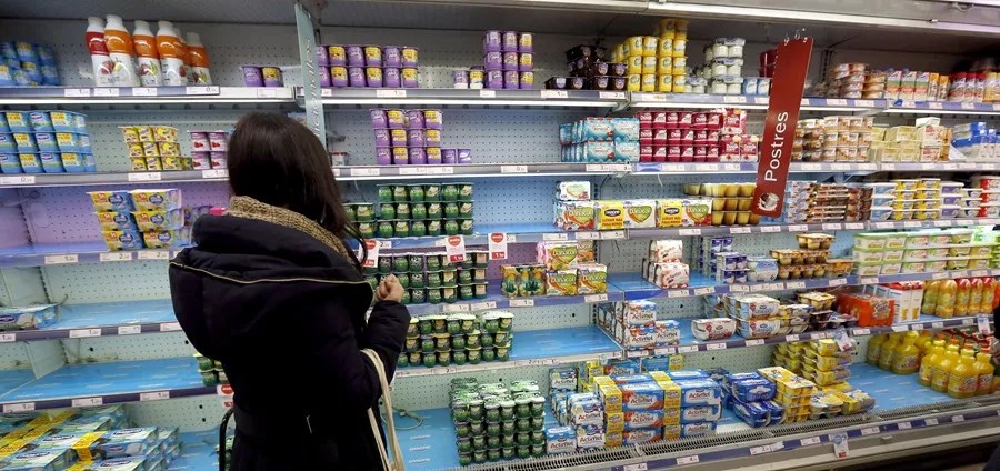 Una mujer mira la fecha de caducidad de un yogur.