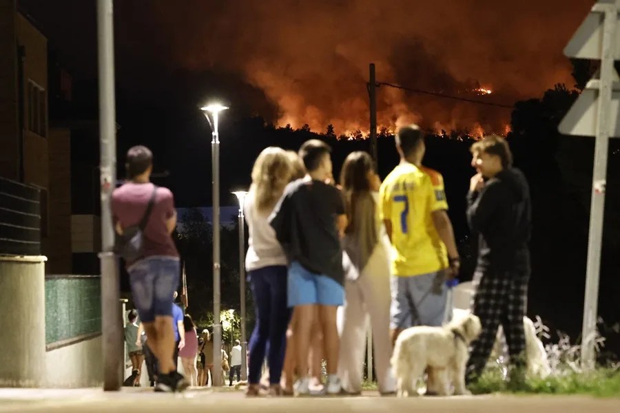 Vecinos de una localidad observan el incendio cerca de sus casas.