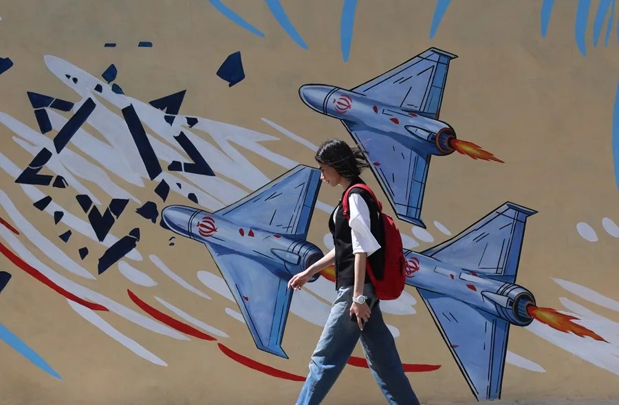 Una mujer iraní pasa junto a un dibujo anti EE.UU e Israel, en Teherán.