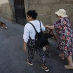 Una mujer mayor pasea con su cuidadora con ayuda de un andador.