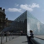 Una mujer se sienta junto a las pirámides del Louvre