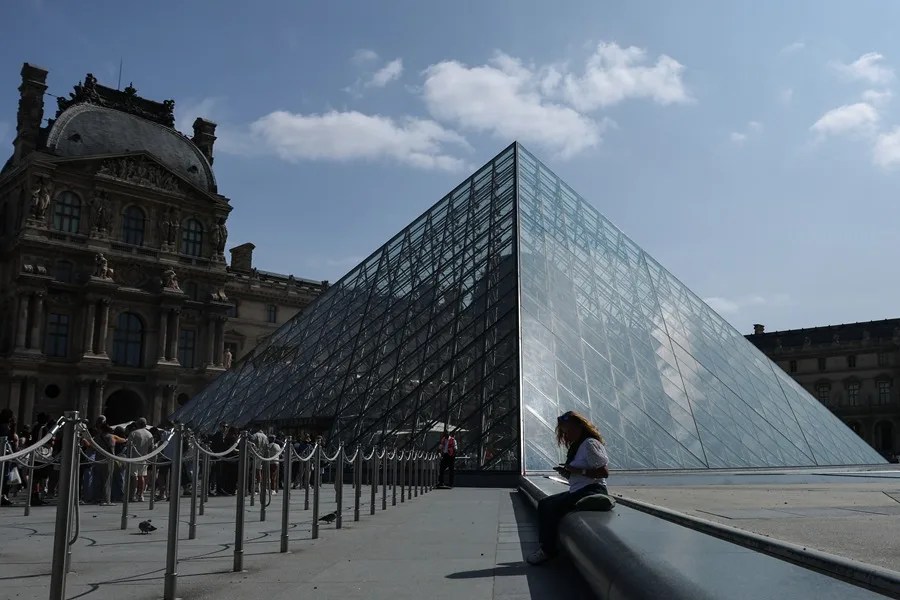 Una mujer se sienta junto a las pirámides del Louvre