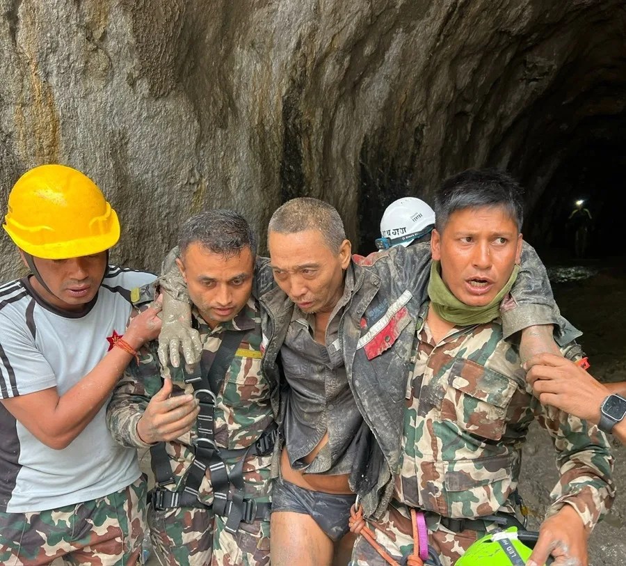 un superviviente chino (segundo por la derecha) siendo rescatado de un túnel en el proyecto hidroeléctrico Upper Trishuli 1