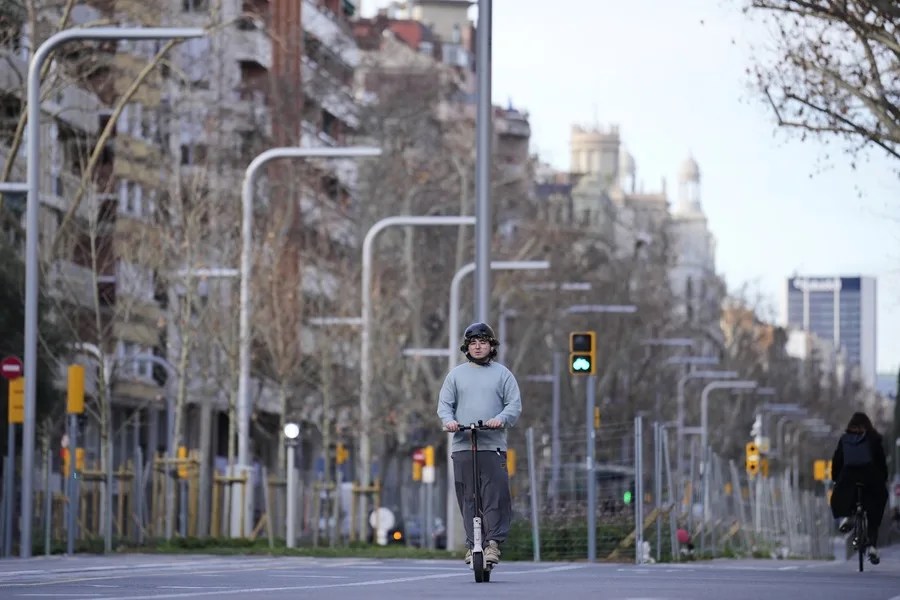 Conductor de un patinete eléctrico circula por una calle de Barcelona.