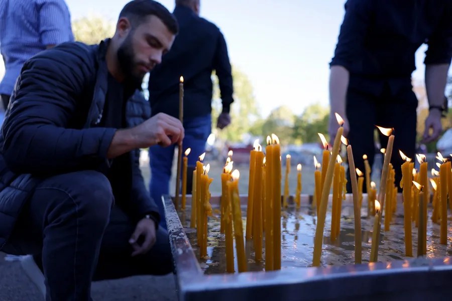 Un hombre enciende velas durante el funeral de Ratko Mladic en Belgrado, Serbia