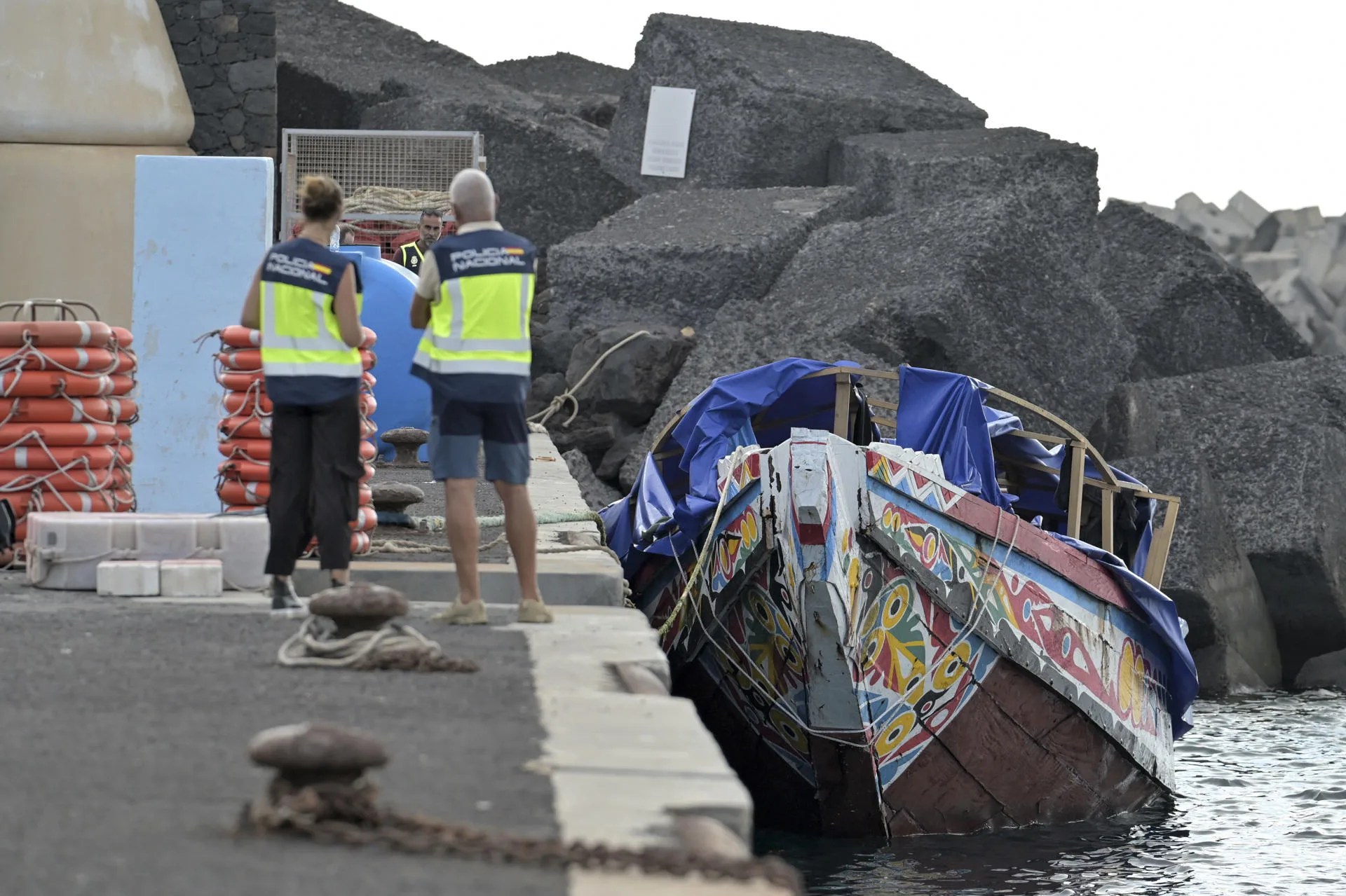 Dos agentes de Policía observan en el puerto de La Restinga el 23 de junio el cayuco en el que llegaron los inmigrantes luego internados en el CIE. EFE/Gelmert Finol