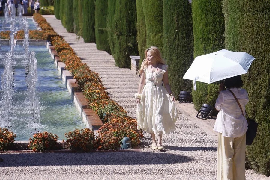 Turistas paseando con paraguas por las fuentes jardines del Alcázar para sofocar el intenso calor.