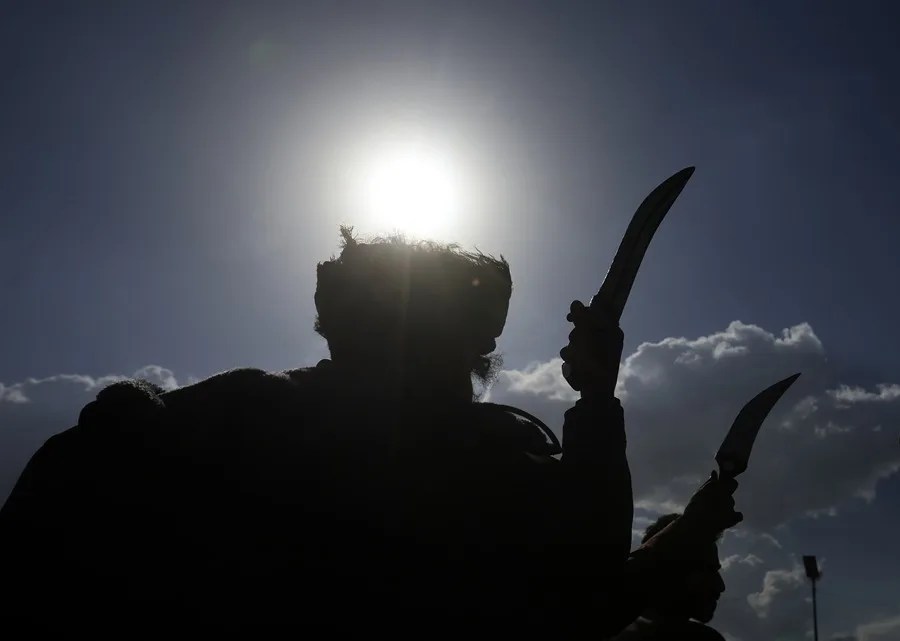 Personas realizan una danza con dagas mientras sus siluetas se recortan contra el cielo en una calle de Sana'a, Yemen