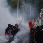 Estudiantes de secundaria permanecen en medio de gases lacrimógenos mientras estallan enfrentamientos entre alumnos y la policía antidisturbios